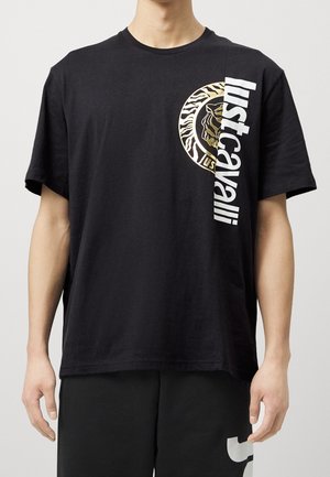 T-shirt en coton noir à coupe ample, avec un motif tigre doré et le texte blanc « Just Cavalli » sur le côté. Manches courtes, col rond.