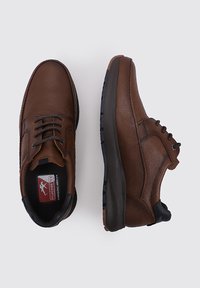 Zapatos de cuero marrón con acabado texturizado, diseño con cordones, suela negra en contraste y cuello acolchado. Presenta el logotipo en la plantilla.