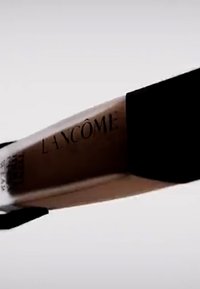 Tuba podkładu o przezroczystej obudowie, czarnym zakrętce i wyrazistym logo "Lancôme". Charakteryzuje się gładką, lekko odbijającą powierzchnią.