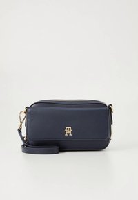 Marineblauwe leren crossbodytas met gouden hardware, ritssluiting en logodetail aan de voorkant. Voorzien van een afneembare riem voor veelzijdigheid.
