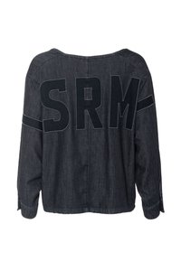 Ciemna koszula dżinsowa o luźnym kroju, szerokim dekolcie i dużym logo „SRM” na plecach. Ma długie rękawy z mankietami zapinanymi na guziki.