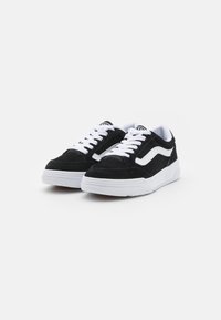 Schwarze Wildleder-Sneaker mit weißen Akzenten, die ein klassisches Schnürdesign und strukturierte Gummisohlen aufweisen. Schlichte und moderne Gestaltung.