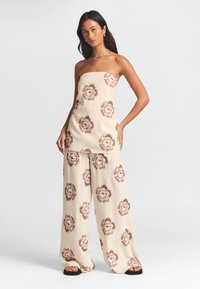 Beige linne strapless topp och vida byxor med bruna blommönster. Lättviktigt tyg med en avslappnad passform och rak silhuett.