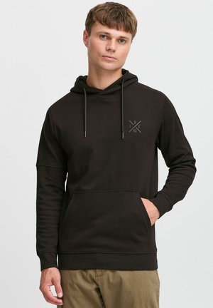 Schwarzer Kapuzenpullover aus einem weichen, strukturierten Stoff. Mit einer Fronttasche und einem subtilen Logo auf der Brust. Lange Ärmel mit gerippten Bündchen.