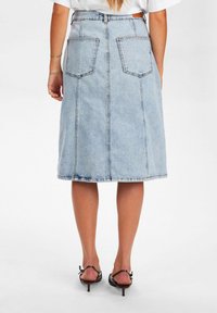 Svetlo modra denim midi krila z visokim pasom, ki vključuje dve zadnji žepki, ravno silhueto in vidno šivane šive ob šivih.