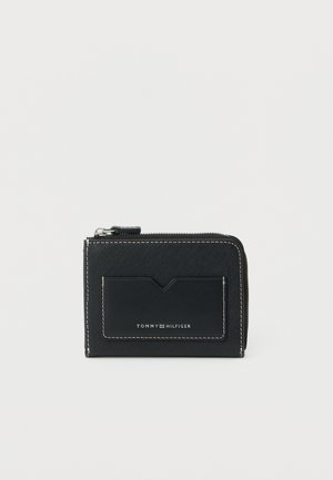 Černá peněženka Tommy Hilfiger na zip s vnějším přihrádkou na karty a kontrastním bílým prošíváním na jednoduchém pozadí.