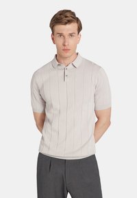 Jasnoszary, krótki polo z rękawami i prążkowanym wzorem, z zapięciem na trzy guziki. Miękki materiał o gładkiej teksturze.