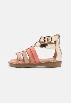 Sandal med stropper i metallisk guld, pink og ferskenfarvede bånd. Glat lædermateriale, justerbar spænde og en flad gummisål.