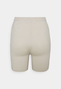 Shorts beiges côtelés avec une taille élastique, présentant une coupe ajustée et une texture lisse, s'étendant jusqu'à mi-cuisse.