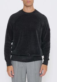 Maglione grigio scuro lavorato a maglia con dettaglio a costine sulle spalle, scollo rotondo e maniche lunghe. Il tessuto appare morbido e testurizzato.