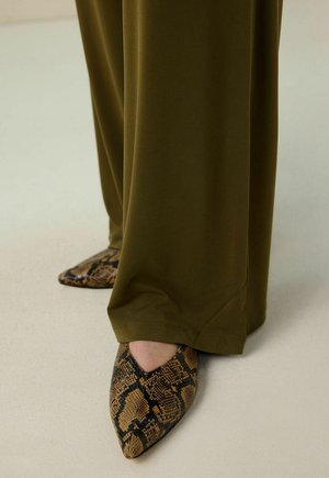 Olive green loose-fitting pants with a smooth texture paired with pointed-toe, brown snake-print flats featuring a textured finish.
