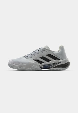 Light grey athletic shoe with black stripes, featuring a textured upper, padded collar, and a transparent accent on the side.