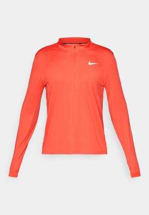 Maglietta sportiva a maniche lunghe con zip, di un vivace corallo, realizzata in tessuto leggero, con il logo Nike bianco sul lato sinistro del petto.