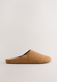 Chausson marron en suédine à enfiler, avec un bout arrondi fermé et un petit talon, présenté sur un fond neutre uni.