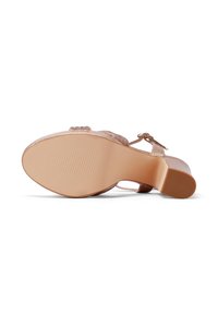Zapato de tacón abierto con tiras y un material superior texturizado en un tono dorado, con una plantilla acolchada y una suela de goma de color marrón claro y suave.