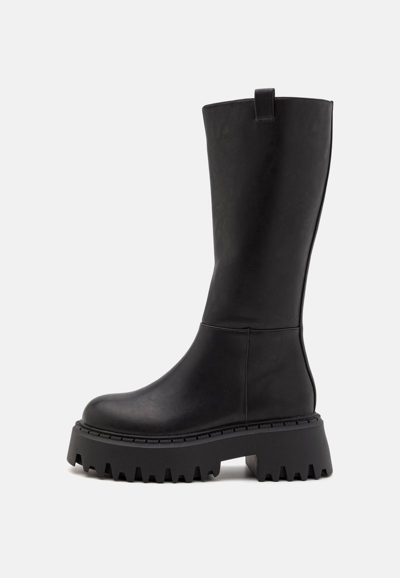Botte noire montant jusqu'au genou avec semelle épaisse et robuste et languette de tirage en haut, vue de profil sur fond blanc.