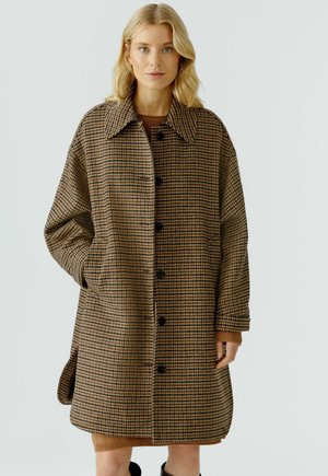 Bruine en zwarte houndstooth-jas met een grote kraag, voorzakken en zwarte knopen, met een losse, oversized pasvorm.