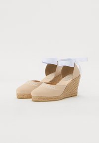 Bežne espadrille sandale na peto z platnenim zgornjim delom, belim logotipom in vezanjem okrog gležnja. Juta ovita petka dodaja teksturo in višino.