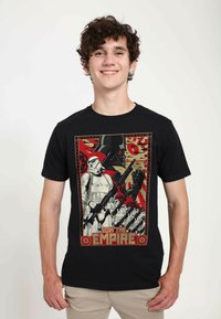 Black cotton t-shirt featuring a graphic print with a Stormtrooper and Darth Vader, surrounded by red and gold accents. Text reads "JOIN THE EMPIRE."