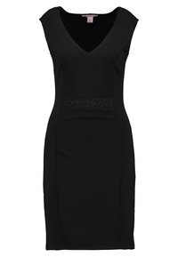 Mustat hihattomat mekko, jossa on V-pääntie, tiukka muotoilu, hienovaraisesti teksturoitu kangas ja koristeellinen helmistä valmistettu vyötärönauha.