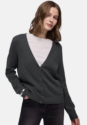 Cardigan gris foncé en maille avec un col en V profond, des boutons à l'avant et des poignets côtelés, associé à un t-shirt rose clair en dessous.