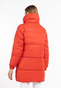 Röd puffjacka med hög krage, quiltad textur och elastiska ärmslut. Har en rak skärning och justerbar passform vid midjan.