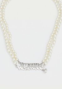 Divslāņu baltu pērļu kaklarota ar sudraba Vivienne Westwood logotipa piekariņu centrā uz balta fona.