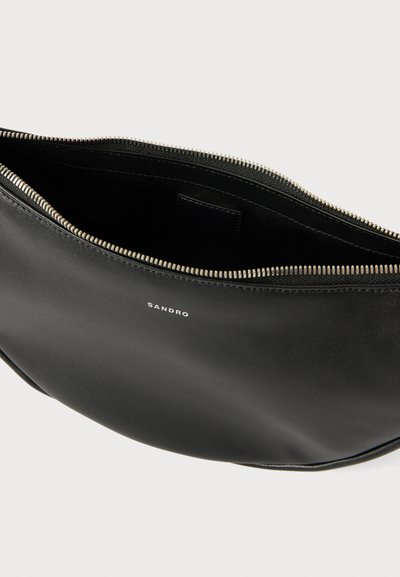Schwarze Leder-Clutch mit glatter Textur, silbernem Reißverschluss und Innenfach. „SANDRO“-Logo geprägt auf der Vorderseite. Schlankes, minimalistisches Design.