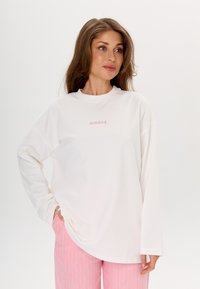 Weißes Sweatshirt mit langen Ärmeln, Rundhalsausschnitt und dezentem, rosafarbenem "MIRONS"-Stickerei in der Mitte. Weicher, glatter Stoff und lockere Passform.