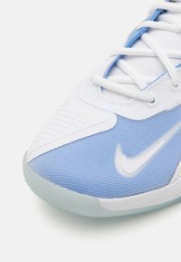 Încălțăminte sport cu un superior din țesătură albă și albastră deschisă, plasă texturată și un logo alb proeminent. Include șireturi albe și talpă din cauciuc.