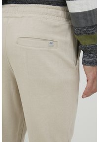 Beige sweatpants lavet af blødt stof. Har en elastisk talje og en baglomme med et lille logo mærke.