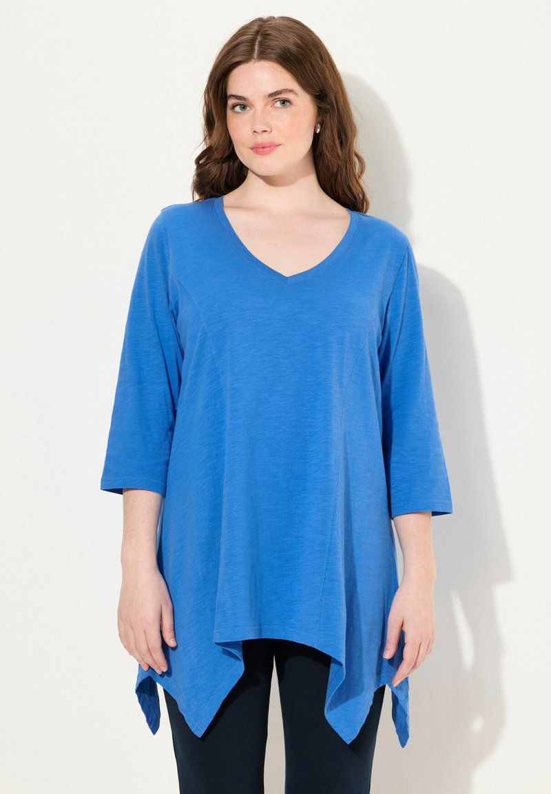 Blaue V-Ausschnitt-Bluse mit Dreiviertelärmeln, ausgestattet mit einem fließenden Design und abgerundetem Saum, hergestellt aus einem weichen, leichten Stoff.