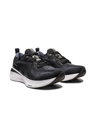 Scarpe sportive nere con tomaia testurizzata, costruzione leggera, suola bianca a contrasto e sistema di allacciatura con accenti di sostegno.