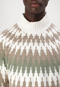 Strickpullover mit hohem Rippkragen, ausgestattet mit einem geometrischen Muster in Offweiß, Beige und Grün. Weicher, strukturierter Stoff.
