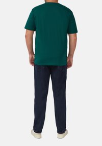 Groene t-shirt met korte mouwen en ronde hals, gedragen met donkerblauwe broek, van katoenmix, met een gladde textuur en een ontspannen pasvorm.