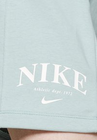 Light blue Nike sweatshirt featuring a prominent white logo and 'Athletic dept. 1972' text. Made of soft, textured fabric with visible stitching.