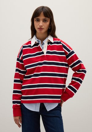Rode langegsmouf polo met witte en marineblauwe horizontale strepen, met een witte kraag en een gedeeltelijke knoopsluiting, gedragen over een blauw gestreept shirt.