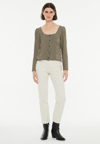 Blusa de manga larga con escote cuadrado en un patrón de cuadros texturizado en marrón y crema, con botones frontales y detalles fruncidos en los hombros.