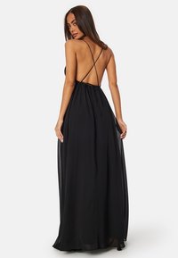 Černé maxi šaty bez rukávů s nízkým výstřihem na zádech, tenkými ramínky a lehkým, průsvitným materiálem pro elegantní vzhled. Obsahují pásek na stažení v pase.