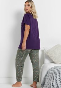 Lila bomullströja med korta ärmar, tillsammans med gröna mönstrade pyjamasbyxor med blommönster och botaniska motiv.