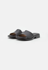 Black leather open-toe slide sandals with low block heels on a white background.