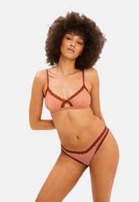 Alushouset yhdistelmä pehmeästä vaaleanpunaisesta kankaasta, jossa maroonit pitsikoristeet. Bralette-mallissa on säädettävät olkaimet ja avainaukko-yksityiskohta; mukana sopivat alushousut.