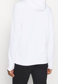 Witte hoodie van zachte stof, met een kangoeroezak, geribbelde manchetten en een capuchon met trekkoord. Eenvoudig ontwerp, zonder zichtbare patronen.