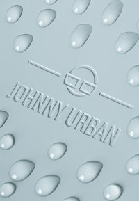 Superficie in silicone grigia con texture a goccia e gocce lucide, e logo "JOHNNY URBAN" in rilievo con un accento circolare sopra il testo.