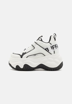 Biało-czarny masywny sneaker z grubą falistą podeszwą, uchwytami do ściągania, graficznym logo na pięcie i boku oraz sznurowanym zapięciem.