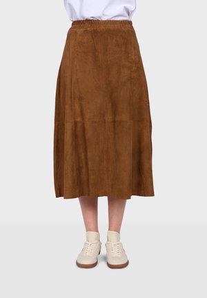 Hnědá semišová midi sukně s elastickým páskem, nošená s bílými teniskami a bílým topem, zobrazena od poloviny stehen dolů.