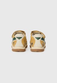 Sandales de sport avec une combinaison de couleurs jaune, beige et verte. Comprend une semelle beige texturée, des sangles ajustables et des accents découpés.