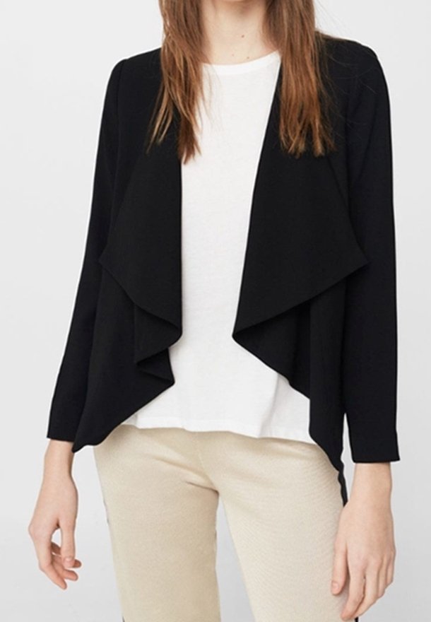 Cardigan noir à ouverture frontale avec un design drapé, manches longues et texture douce, porté sur un haut blanc et un pantalon beige.