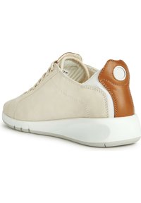 Zapatillas de ante beige con suela blanca y acento de cuero marrón en el talón. Presentan un diseño de cordones y un forro de tela a rayas.