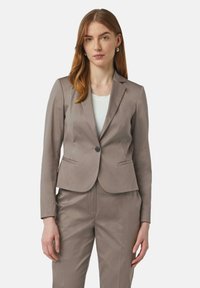 Lichtbruin op maat gemaakte blazer met een enkele knoopsluiting, twee voorkanten zakken en lange mouwen, gecombineerd met bijpassende broek. Soepele stof textuur.